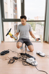 Vertical portrait of housekeeper kneeling on floor, holding cordless window vacuum cleaner and wiper, preparing robot window cleaners and other appliances for cleaning windows in modern apartment