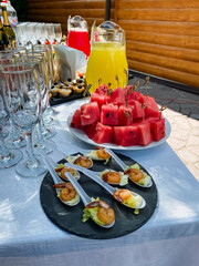 There is a table that has been set up with a plate filled with delicious watermelon slices and several spoons of various types of food arranged on it for everyone to enjoy