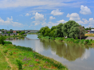 Fototapeta premium Water cycle: The Mures river as it passes through the Aleea Carpati area, with cumulus clouds in the blue sky
