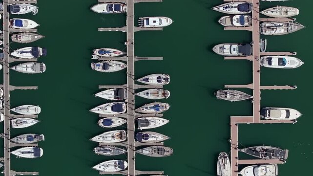 Aerial view of a marina with yachts and boats neatly moored in parallel rows, seen from directly above.