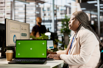 African american company employee creates business strategy next to isolated screen, analyzing data for a financial report. Global expansion project development, enterprise solutions.