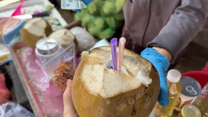 A tourist girl holds 25,000 Vietnamese dong in her hands and plans to buy a coconut at a local night market in Asia. High quality 4k footagetravel buy income poverty tropical fruits