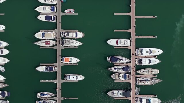 Aerial view of a marina with yachts and boats neatly moored in parallel rows, seen from directly above.