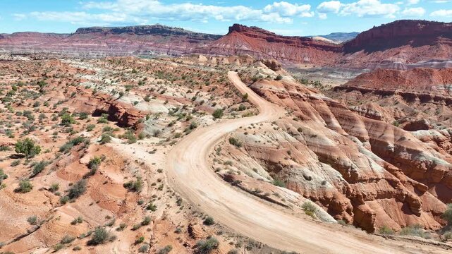 Aerial Winding Dirt Road Red Desert Formations Tracking Shot