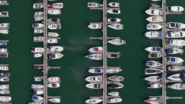 Aerial view of a marina with yachts and boats neatly moored in parallel rows, seen from directly above.