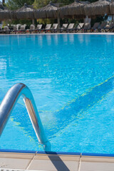 Calm blue swimming pool with inviting steps on a sunny day at a leisure resort