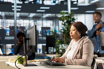 Confident businesswoman at her office desk working on report writing and answering emails,...