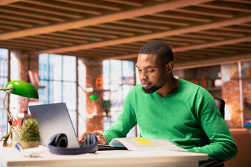 Man at home office desk using laptop, drafting contracts, outlining terms, writing clauses,...