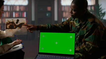 Military trooper studies Rorschach inkblot illustration next to green screen in therapy with psychologist, addressing PTSD and trauma recovery problems. Psychological support. Camera A.