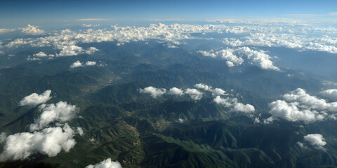 Fototapeta premium Aerial view of land and clouds captured from an airplane, showcasing the stunning interplay of terrain and cloud formations visible during the flight from the airplane perspective.