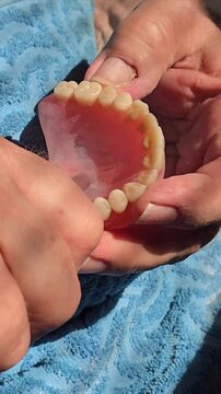 The video shows hands holding a tool gently smoothing the denture before the final polishing stage. 4K video