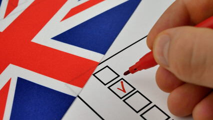 Person uses red marker to mark choice on ballot. Democratic elections in UK. Union Jack in background. Citizens express political will through voting process, strengthening democratic institutions