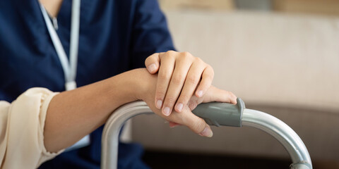 Caregiver assisting elderly woman with mobility aid at home