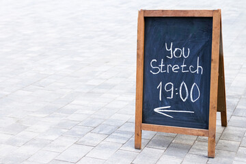 Outdoor Chalkboard Sign Advertising Stretching Class at 19:00