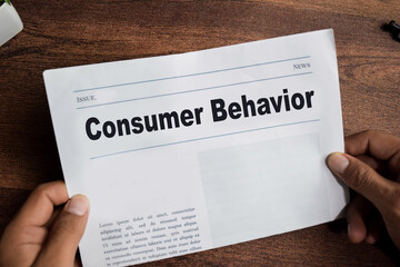 Consumer behavior text in headline isolated on wooden table. Newspaper concept