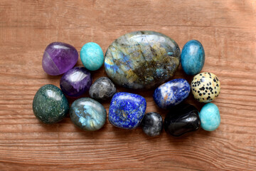 Polished labradorites, amethysts, lapis lazuli, kyanites on a wooden background. Beautiful natural stones, healing crystals, semi-precious stones.