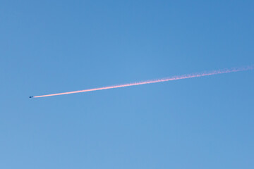 Jet plane leaves a contrail trail during sunset that looks like fire