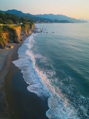Dramatic coastal view featuring a rocky beach, green hills, and mountains in the distance.