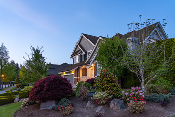 Two story stucco luxury house with nice Spring blossom landscape at night in Vancouver, Canada, North America. May 2025.