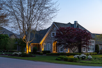 Two story stucco luxury house with nice Spring blossom landscape at night in Vancouver, Canada, North America. May 2025.