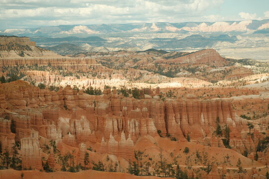 Layered rock formations, hoodoos, red cliffs at bryce canyon national park utah with blue skies and puffy clouds and trees