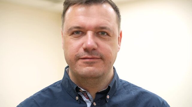A man in a navy shirt transitions from a composed expression to an intense grimace of anguish, then returns to a calm state.