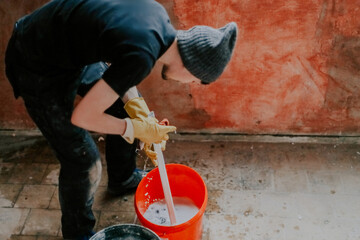 A worker washes the plastic part of the frame with a sponge in a bucket.