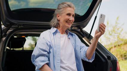 Happy smiling elderly senior mature Caucasian woman tourist automobile driver female blogger...
