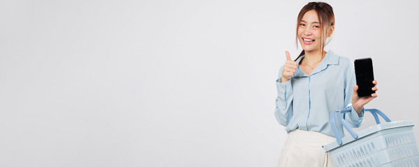 Shopping in supermarket, Asian woman holds basket and mobile phone screen show thumb up smiling and...