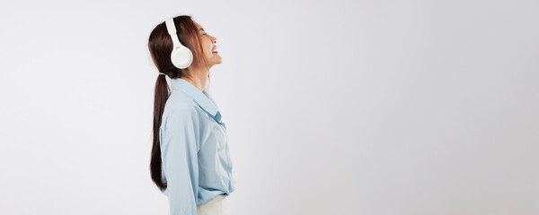 Happy young woman enjoying music, side profile shows eyes closed and smile, headphones on as she...