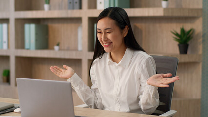 Happy laughing Asian Korean Chinese woman female worker Japanese girl boss businesswoman talking laptop pc waving hand hello gesture video call online conference computer business meeting in office