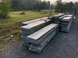 Pile of left over thin long concrete masonry block slabs, on the road side