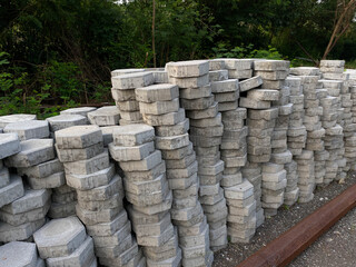 Pile of hexagonal pavers, flooring or concrete block paving, side view, on the edge of green trees