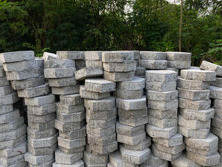 Pile of hexagonal pavers, flooring or concrete block paving, side view, on the edge of green trees