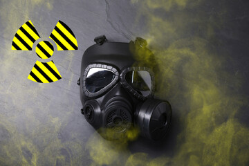Radiation threat. Gas mask, radioactive sign and smoke on grey background, top view