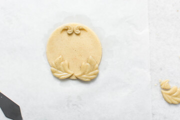 overhead view of vanilla sugar cookie dough being decorated on parchment lined tray, top view of plain cookie dough, process of making sugar cookies