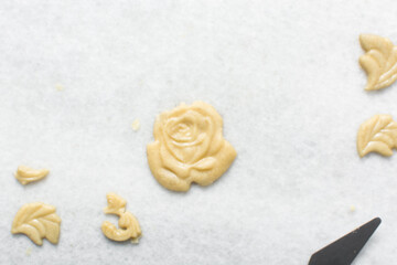 overhead view of vanilla sugar cookie dough being decorated on parchment lined tray, top view of plain cookie dough, process of making sugar cookies