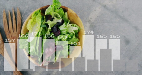Showing wooden bowl of green-purple salad sitting on counter featuring utensils chart with numbers