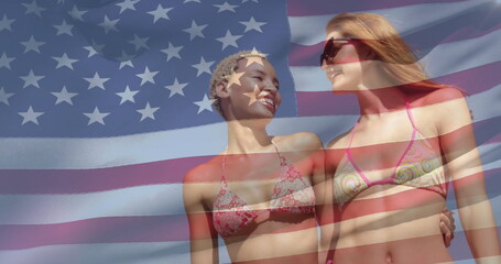Smiling pair of adult women hugging waists at beach, with bikinis, sunglasses and US flag overlay
