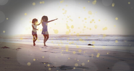 Balancing mother and daughter dancing along sandy beach at sunset, with sunset glow, copy space