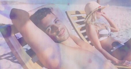 Relaxing adult couple sunbathing on beach lounge chairs, with striped bikini sunglasses and trunks