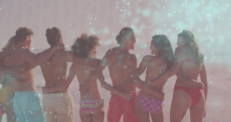 Standing six friends linking arms on sandy beach at sunset, with swimwear and ocean surf