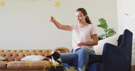 Woman starting pet training by raising treat above dog and lowering to nose golden stars drifting