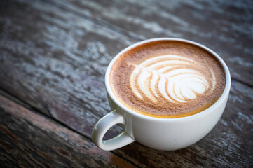 Cup of hot latte coffee on wooden table.