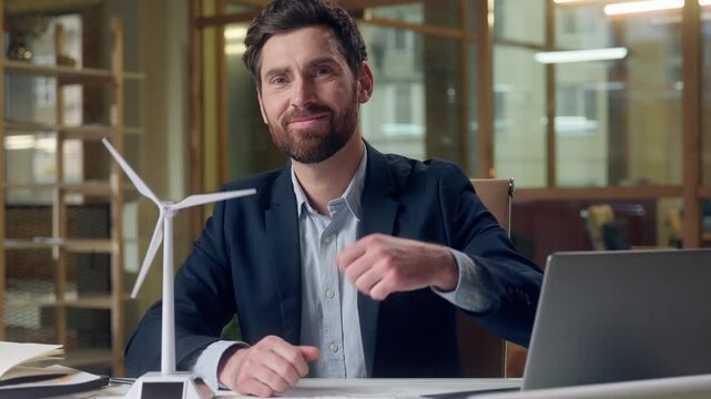 Cheerful Caucasian business man laptop windmill project showing thumb up gesture approval recommendation businessman male guy green energy environment wind turbine generate fuel nature sources office