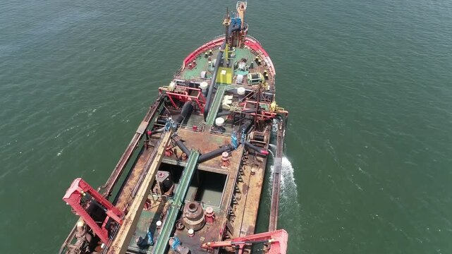 Drone footage capturing a suction dredger ship sailing at sea, showing equipment and machinery used in large-scale dredging operations