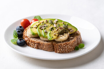 Avocado toast with banana, sunflower seeds, pumpkin seeds, sesame seeds, blueberries and tomatoes, Healthy food