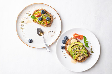 Top view of avocado toast with banana, sunflower seeds, pumpkin seeds, sesame seeds, blueberries, tomatoes and honey, Healthy food