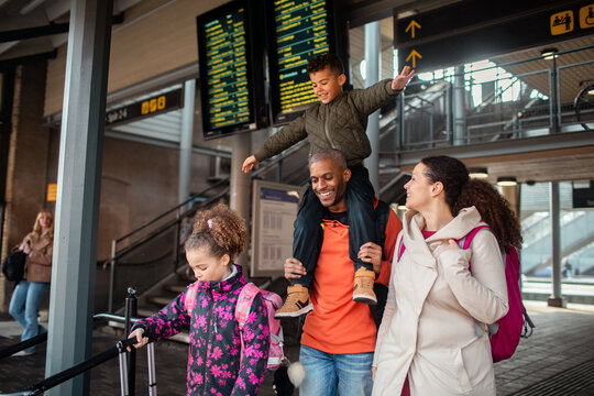 Young multiracial family traveling together on their holiday vacation in a train station