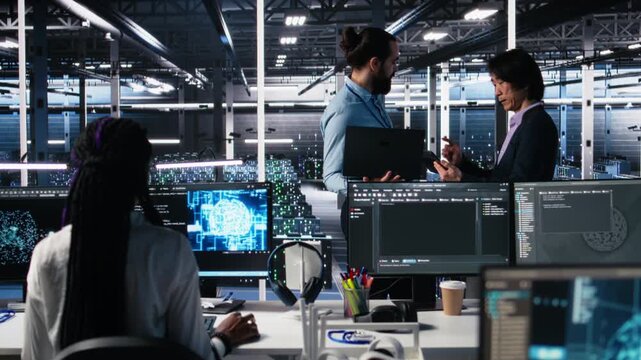 Data center manager supervising work done by programmers working on neural network software. Server hub supervisor overseeing IT staff members implementing deep learning tech, camera A